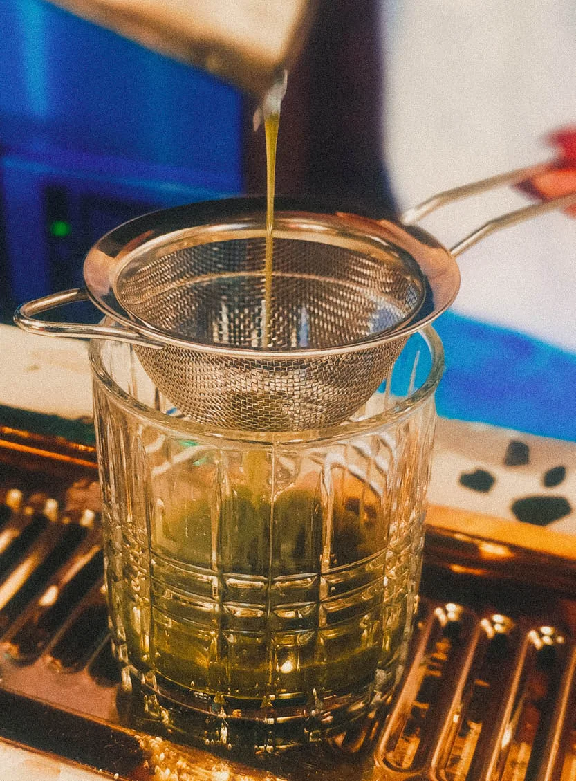 Straining matcha into a glass using a fine mesh sieve.