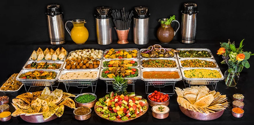 Indian buffet spread with samosas, naan, curries, chutneys, and fresh fruit