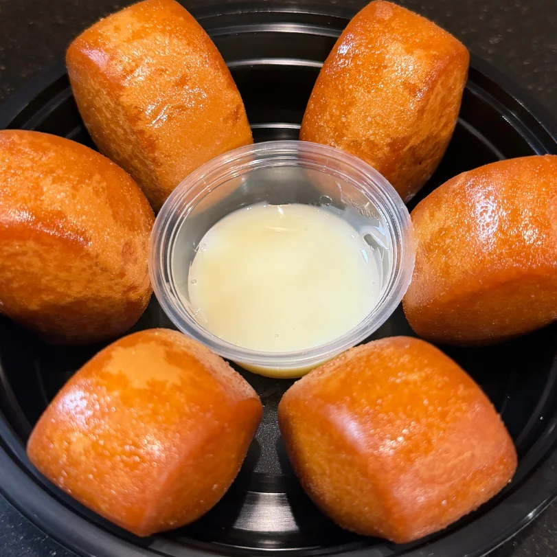 A plate of golden brown rolls with a small cup of dipping sauce.