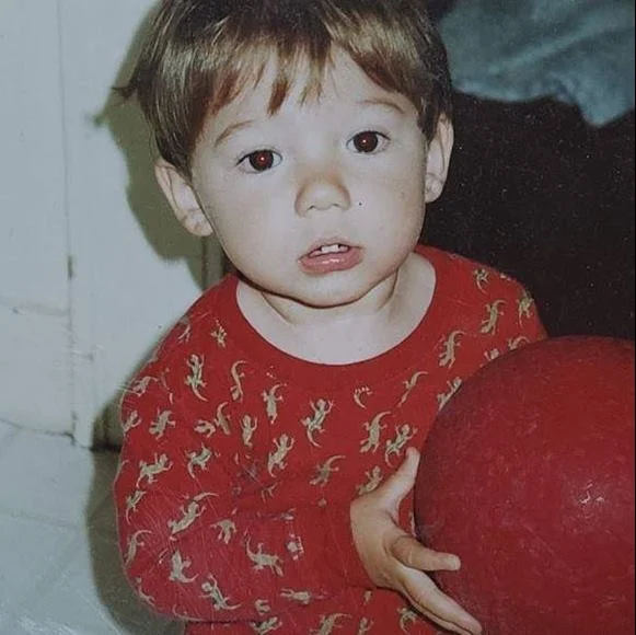 Young child holding a red ball in a cozy indoor setting