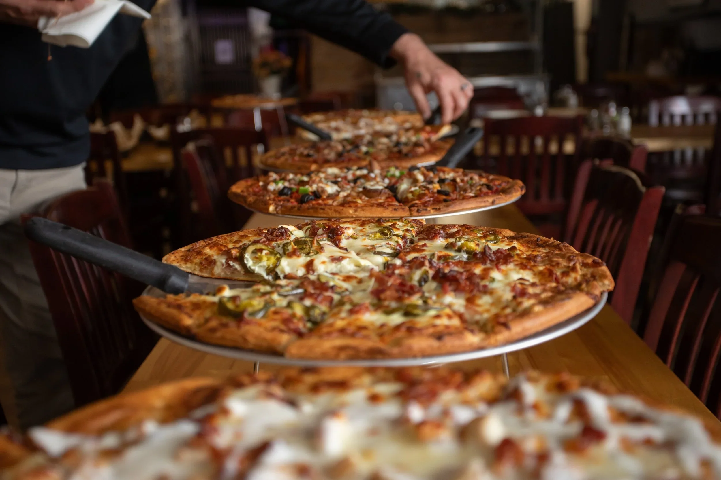 Multiple American-style pizzas on serving trays in a restaurant