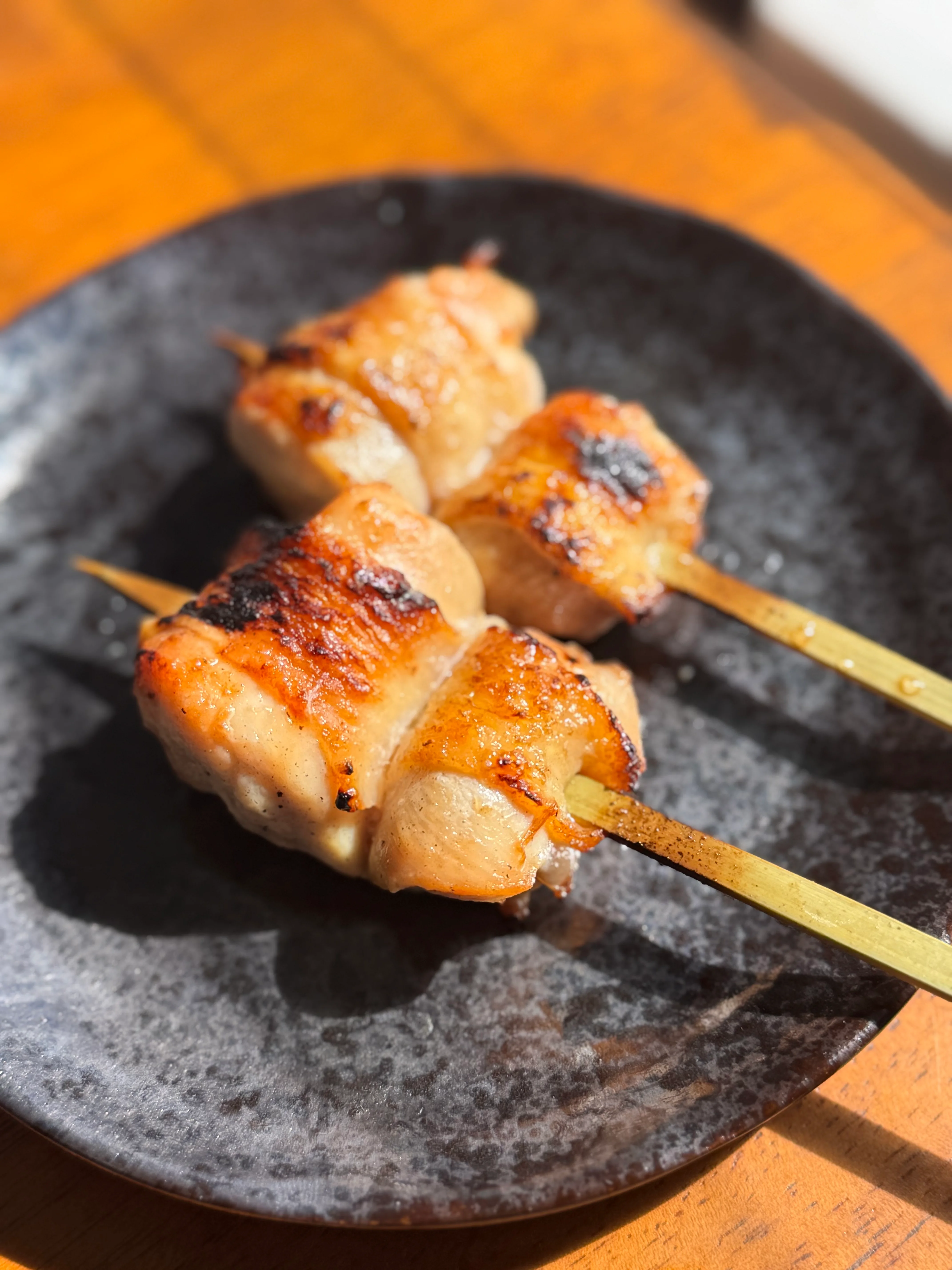 Grilled yakitori chicken skewers on a black plate