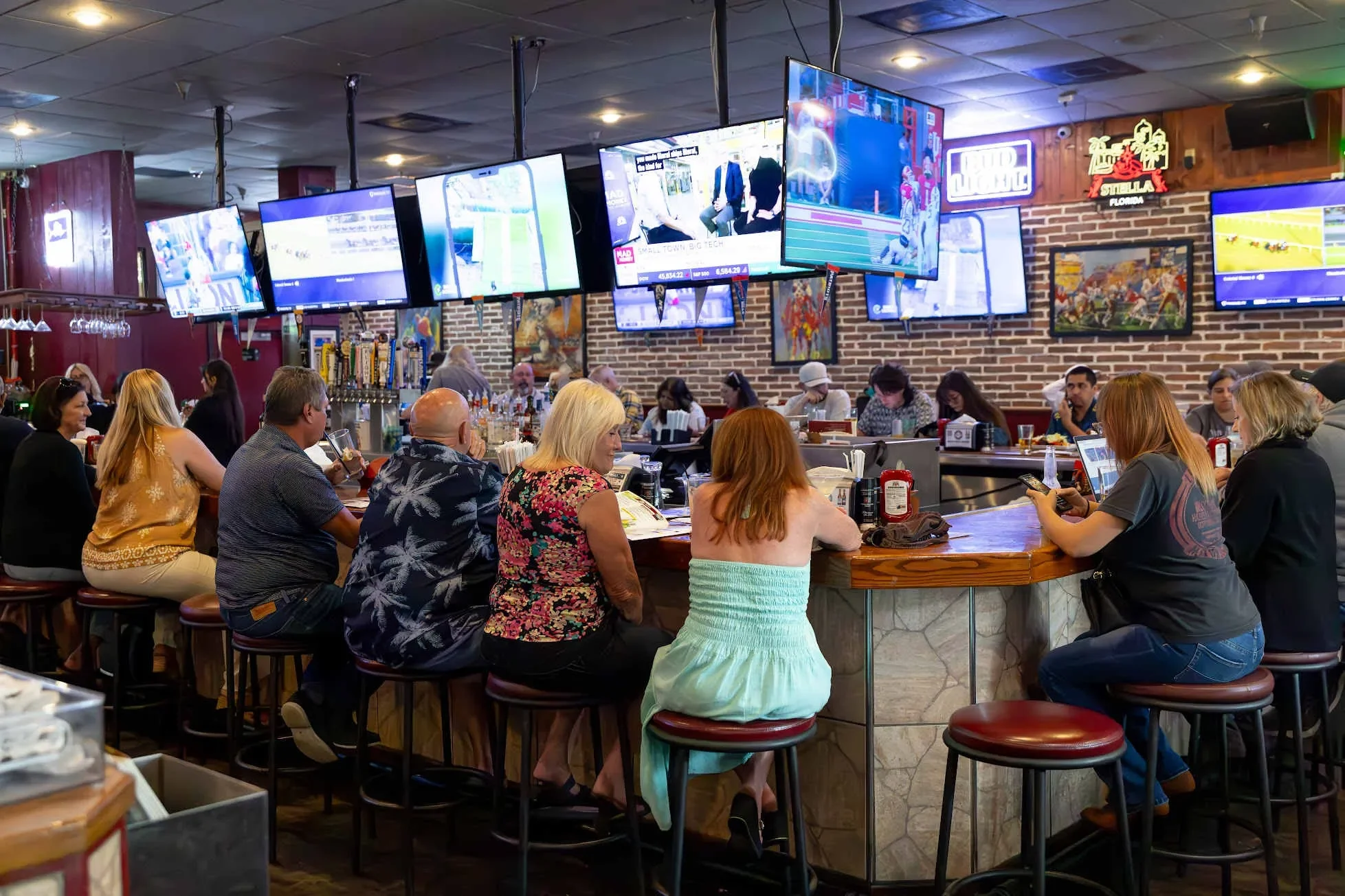 Lively bar scene with patrons enjoying drinks and sports on multiple screens