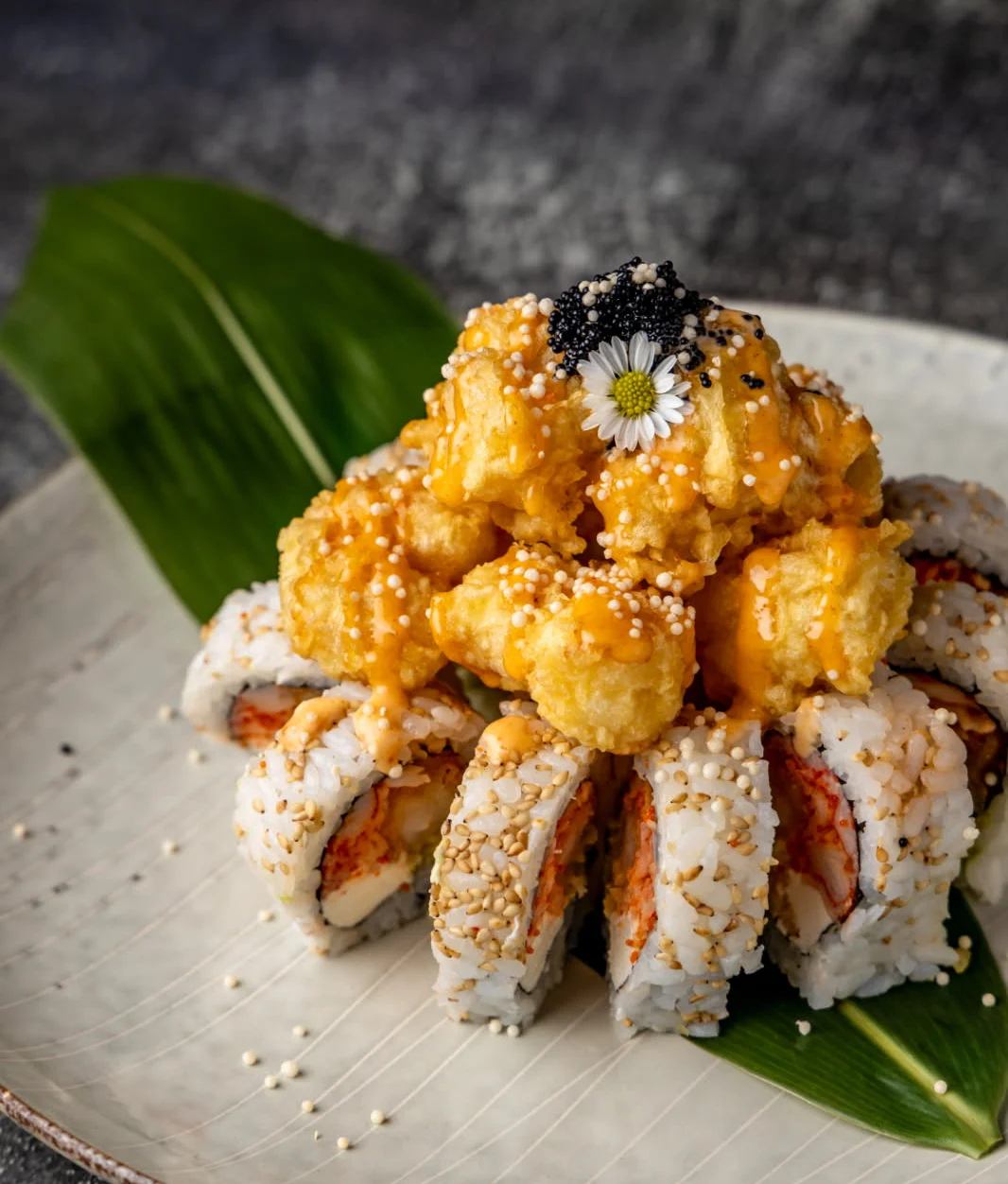 Japanese sushi roll topped with tempura and spicy sauce