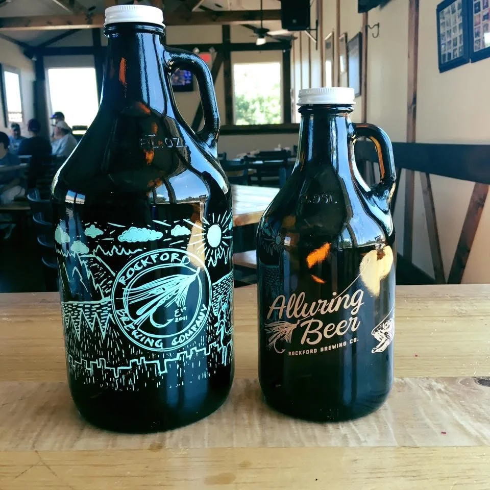 Two decorative beer growlers on a wooden table in a brewery