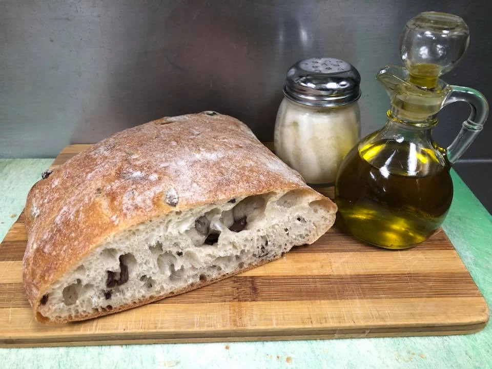 A rustic display of sliced bread accompanied by olive oil and a shaker of salt.