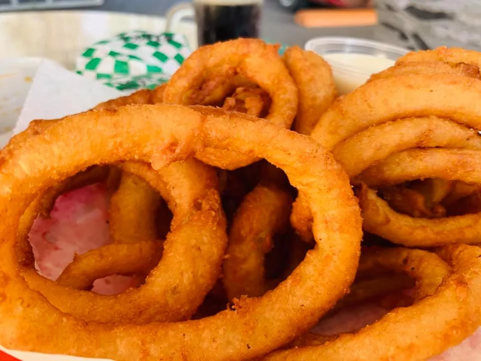 A close-up of crispy golden-brown onion rings piled together, showcasing their crispy texture.