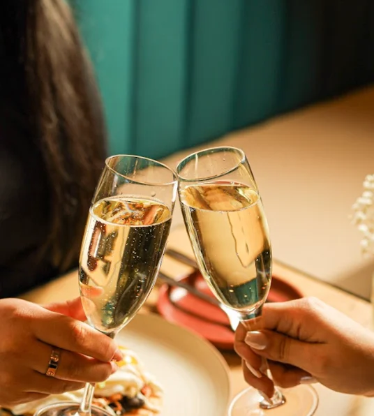 Cheers with champagne flutes in a cozy restaurant setting