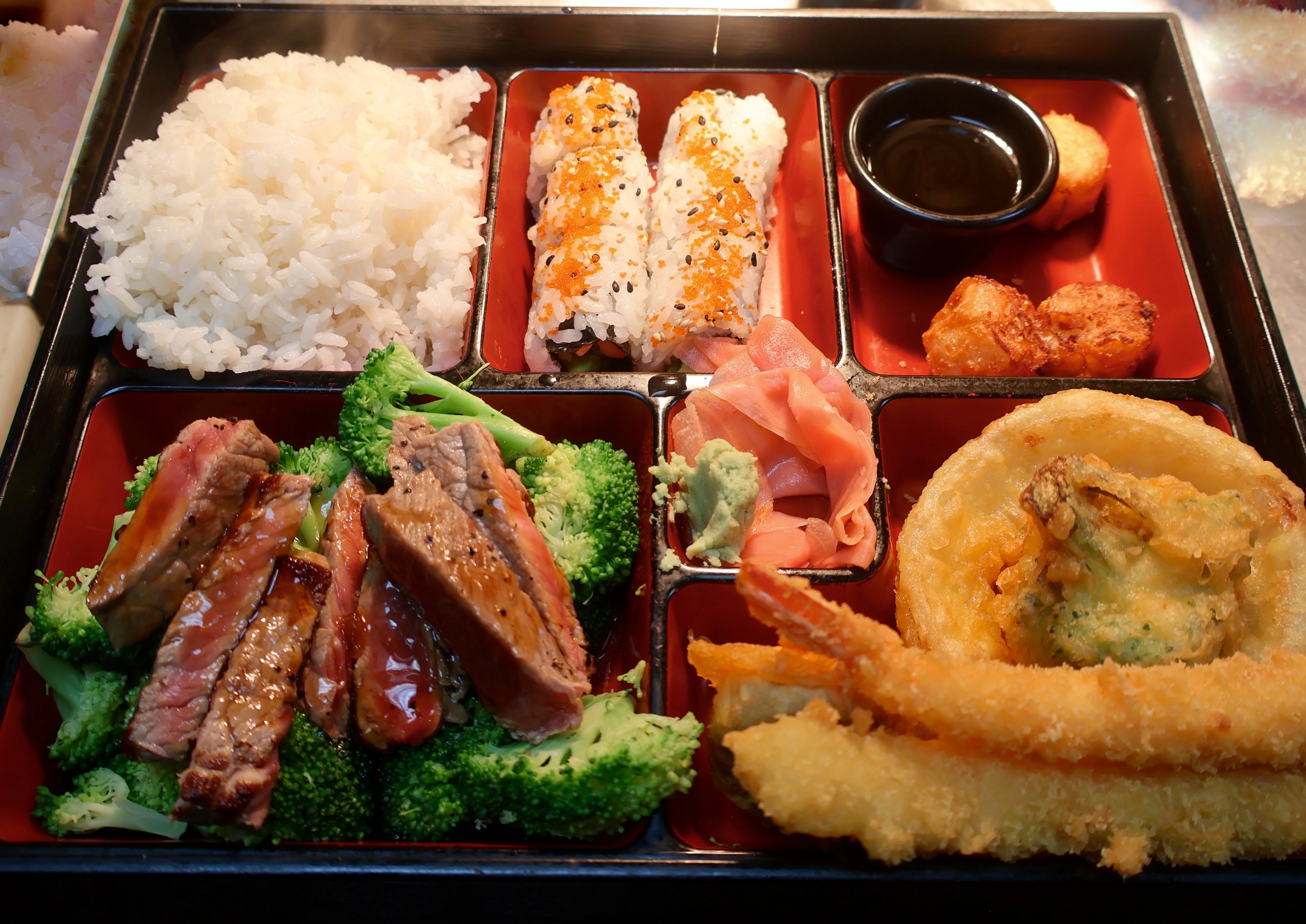 Japanese bento box with grilled steak and sushi rolls
