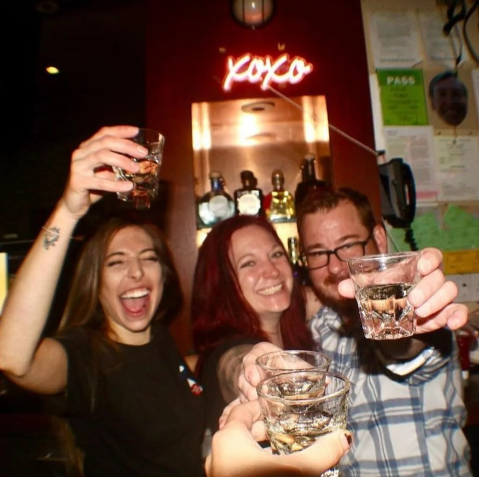 Friends toasting with shots at a lively bar