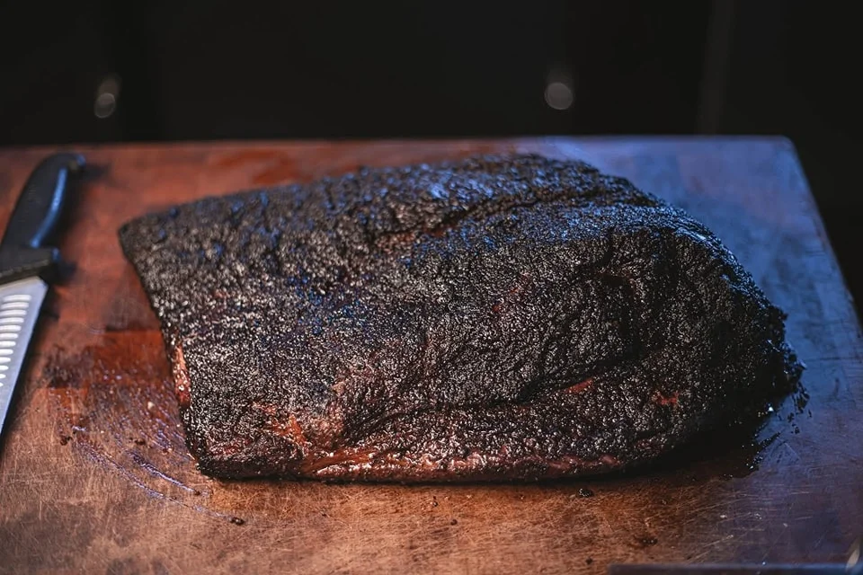 Smoked brisket resting on a wooden cutting board