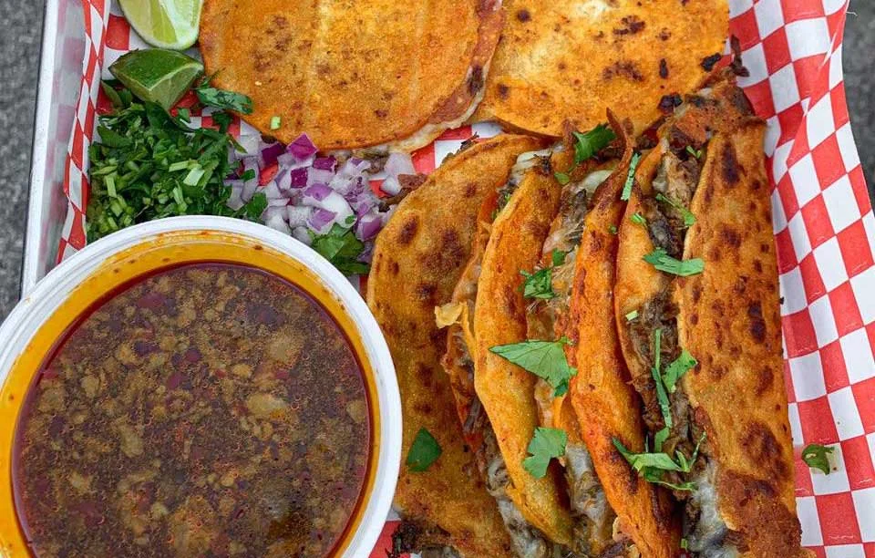 Delicious Mexican tacos with consommé and fresh toppings