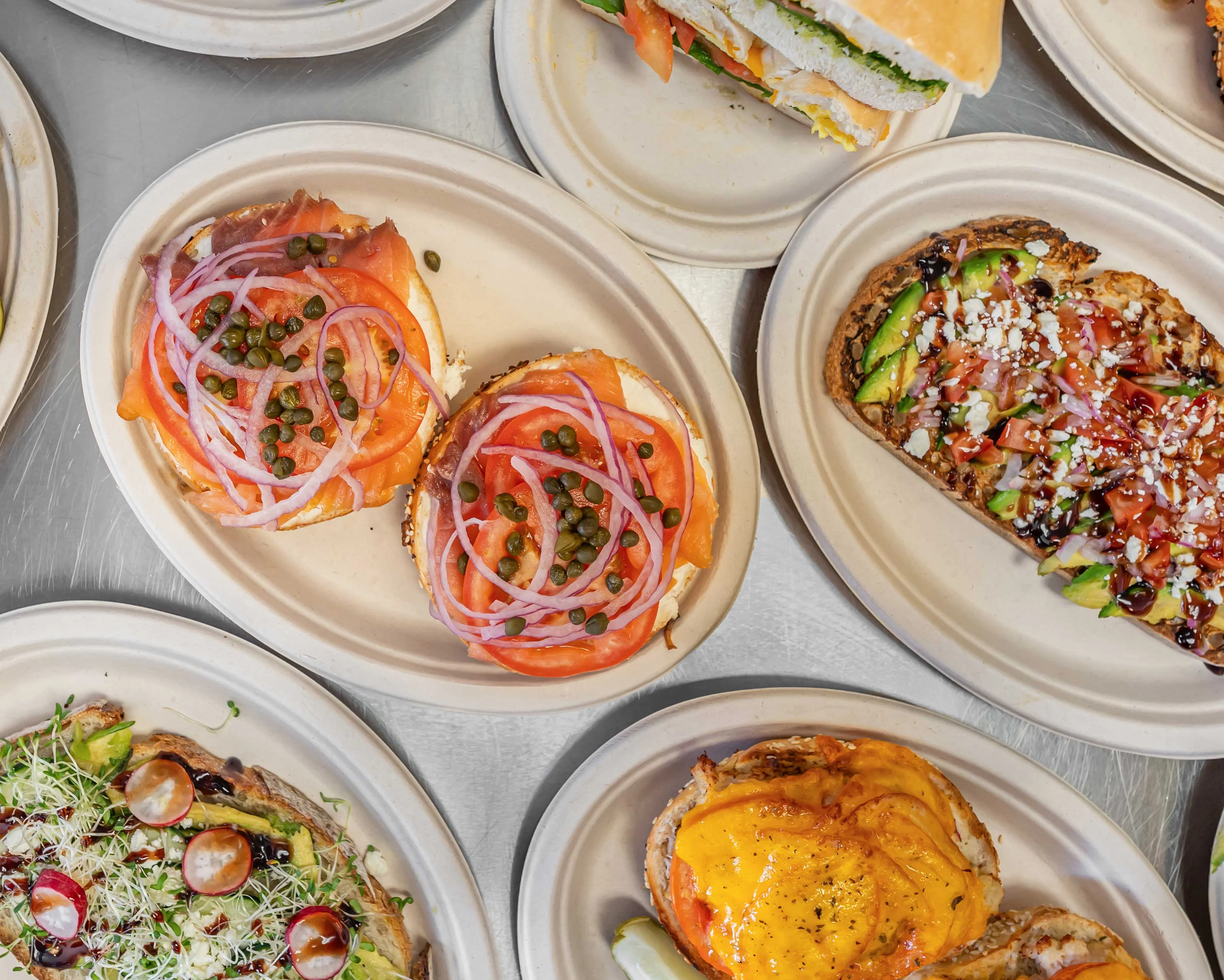 Assorted open-faced sandwiches and bagels on eco-friendly plates