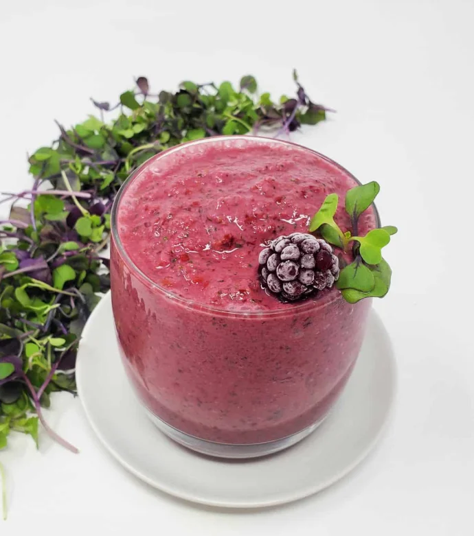 Berry smoothie in a glass garnished with mint and blackberries