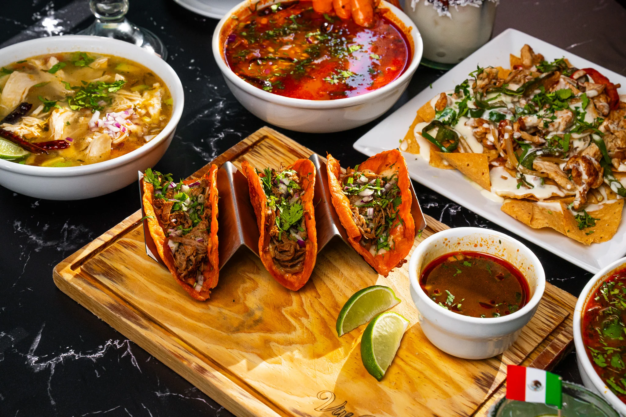 Colorful Mexican tacos with broth and nachos on a wooden platter