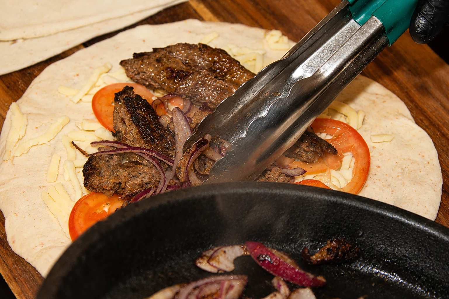 Grilled beef shawarma being prepared in a flatbread