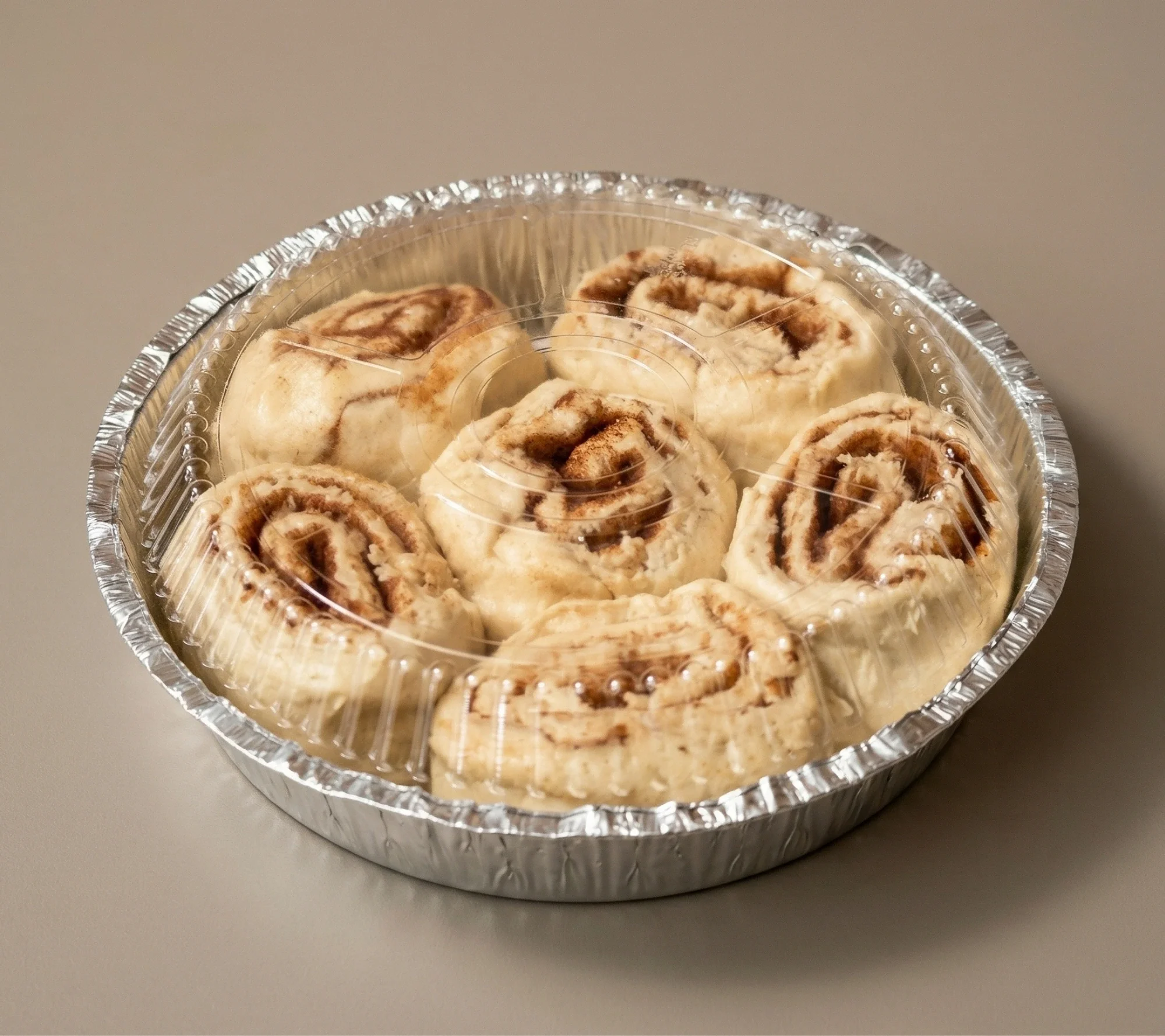 Delicious cinnamon buns topped with icing on a wooden table.
