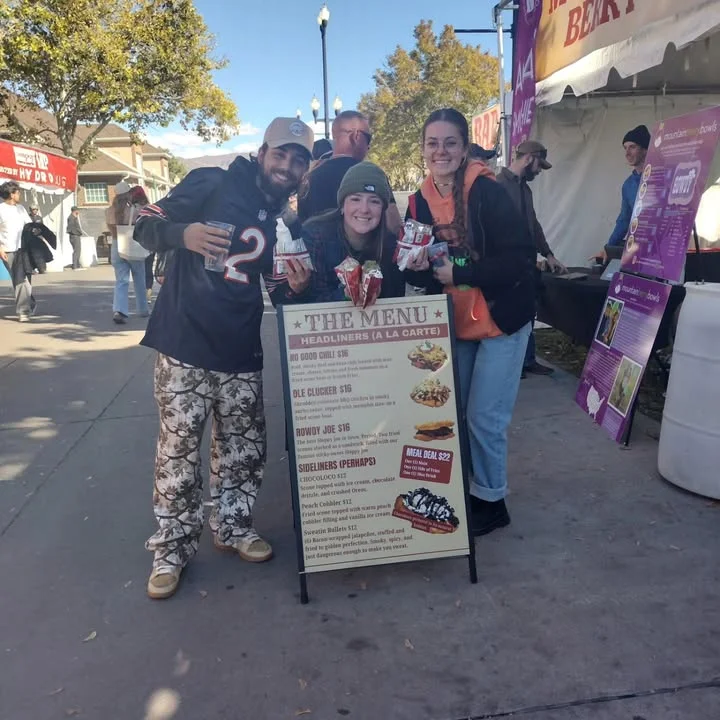 Friends enjoying food at a festival with a menu board