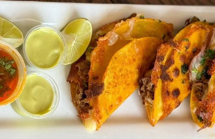 Crispy Mexican quesabirria tacos with sauces and lime