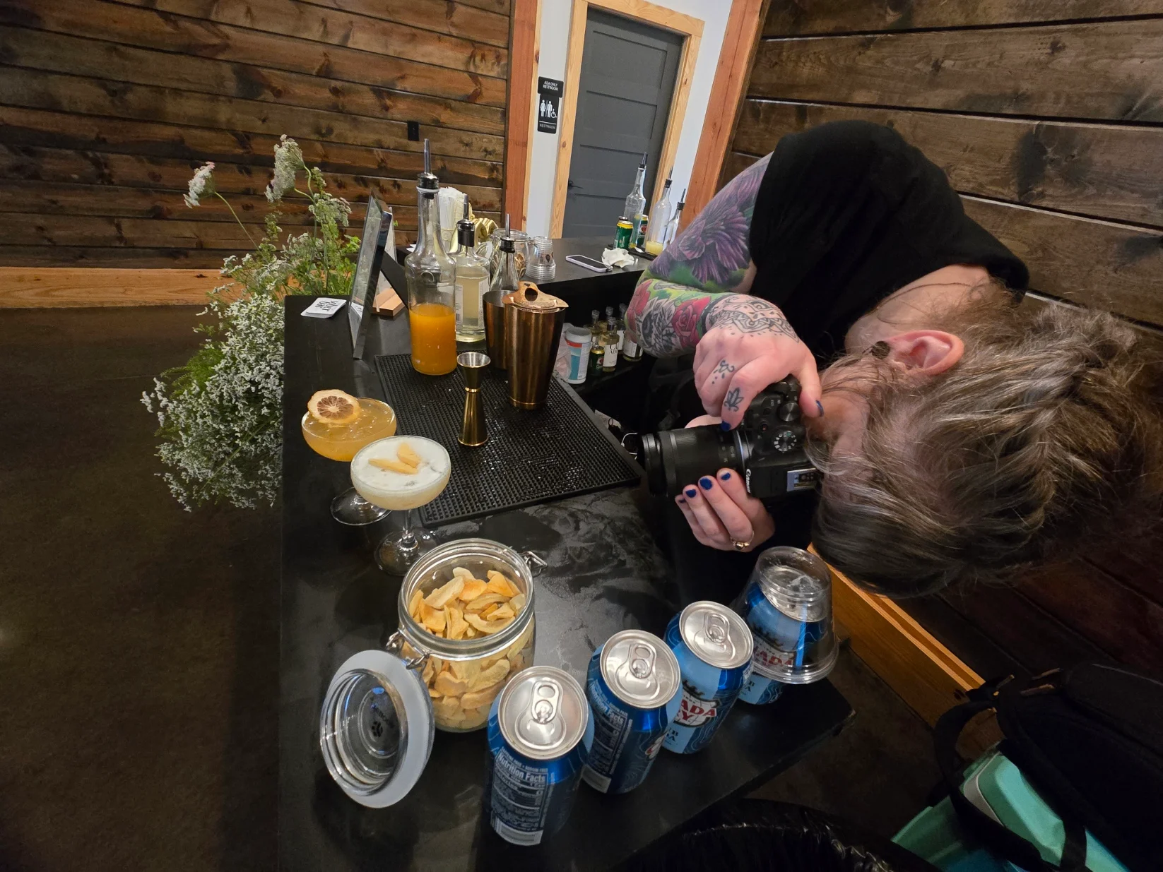 Bartender photographing cocktails at a stylish bar
