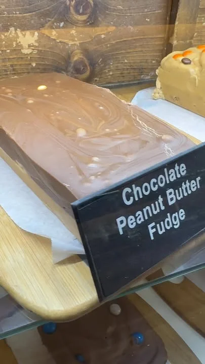 A block of chocolate peanut butter fudge displayed in a glass case, labeled clearly for customers.