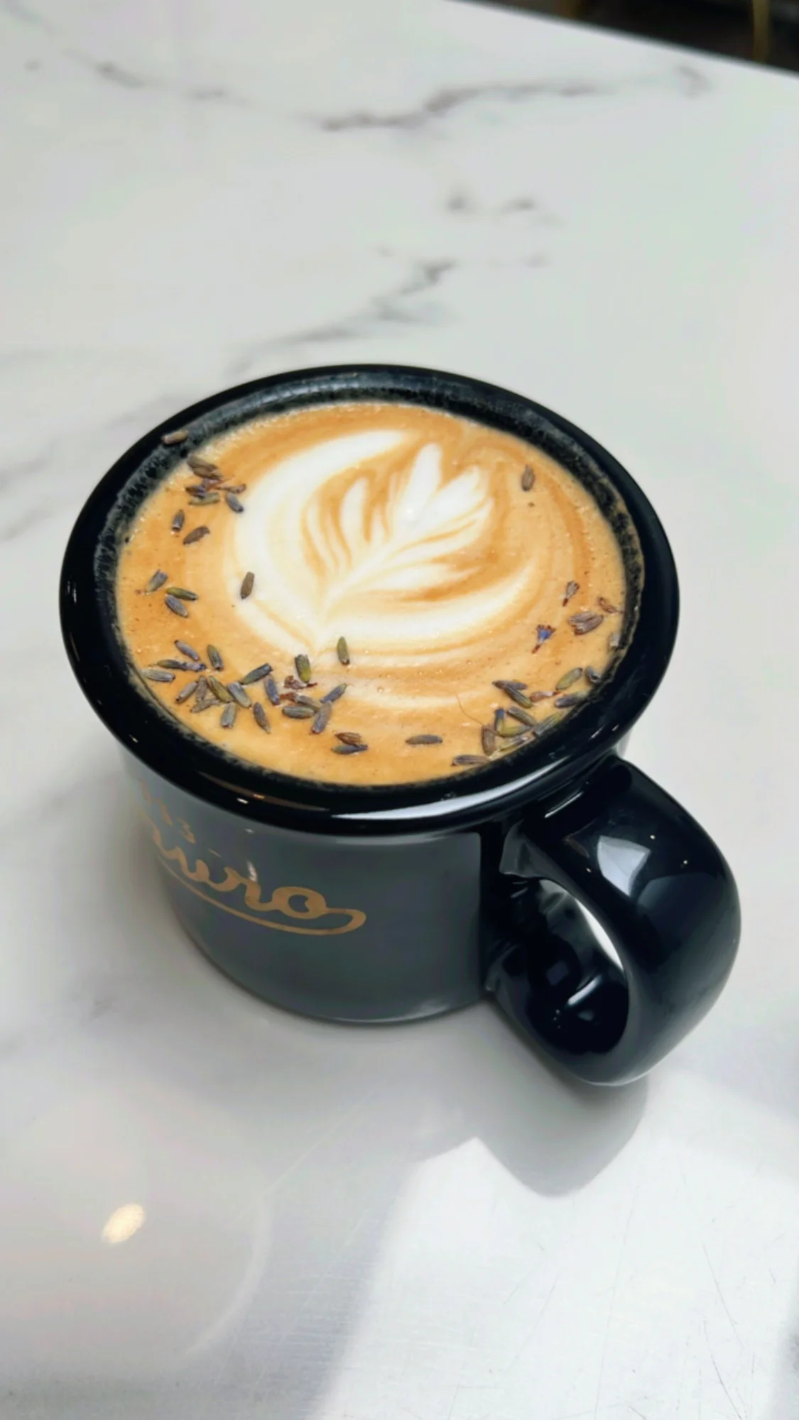 Lavender latte art in a black mug