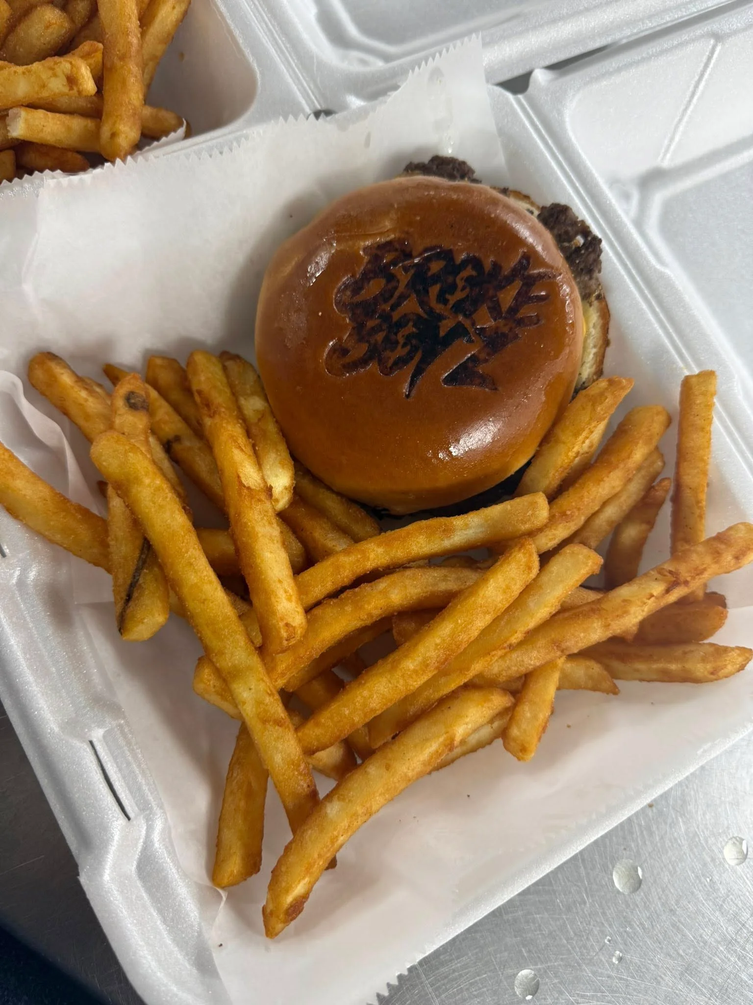 Juicy burger with fries in a takeout container