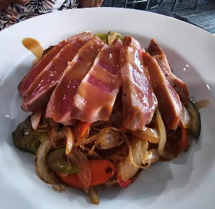 Sliced duck breast on a bed of stir-fried vegetables