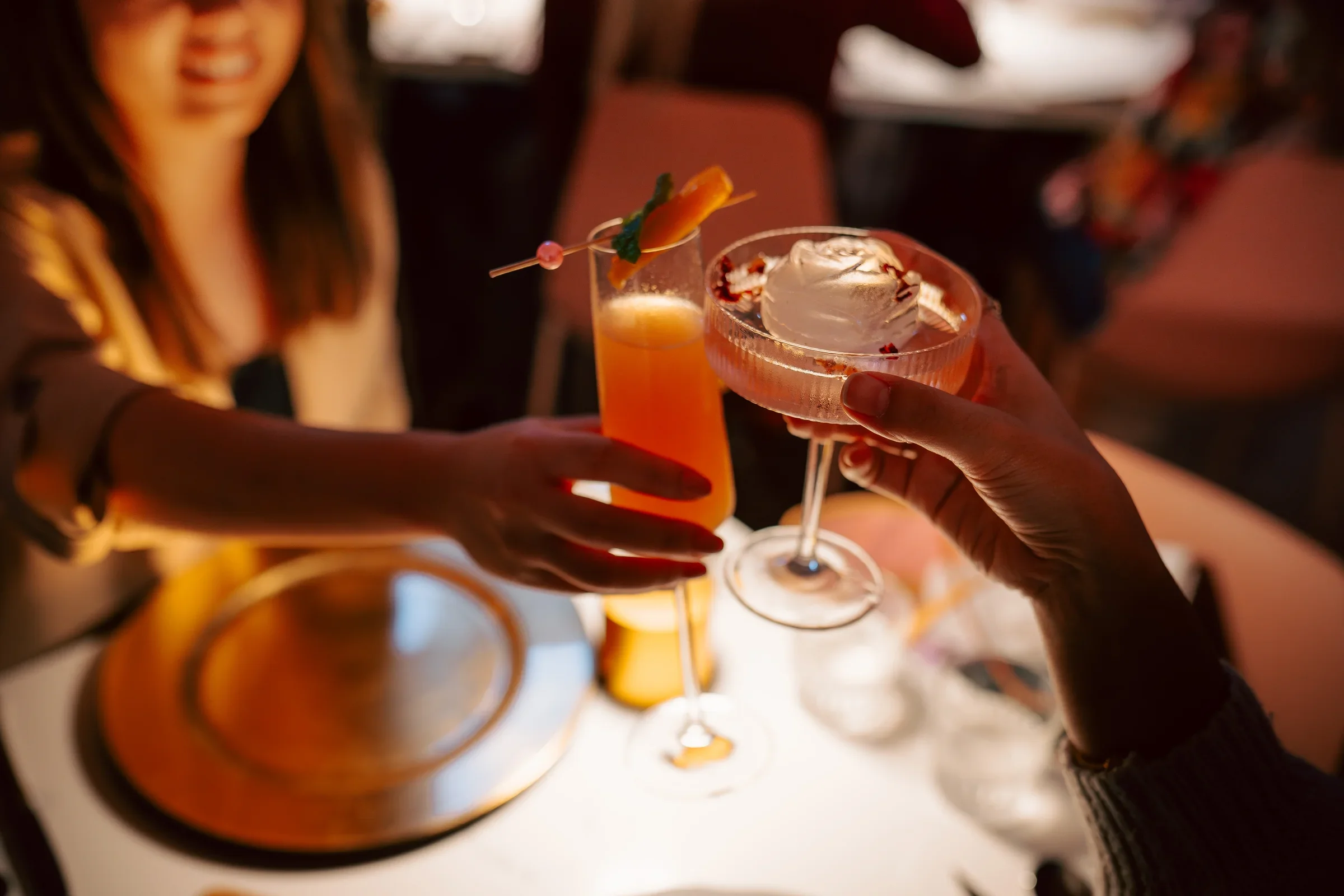 Cheers with colorful cocktails in a cozy restaurant setting