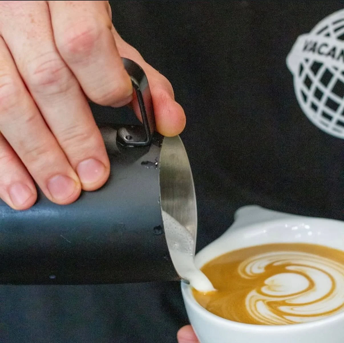 Barista pouring latte art into a cup of coffee