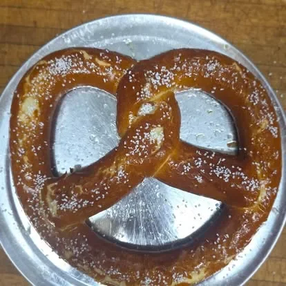 Soft German pretzel with coarse salt on a metal plate