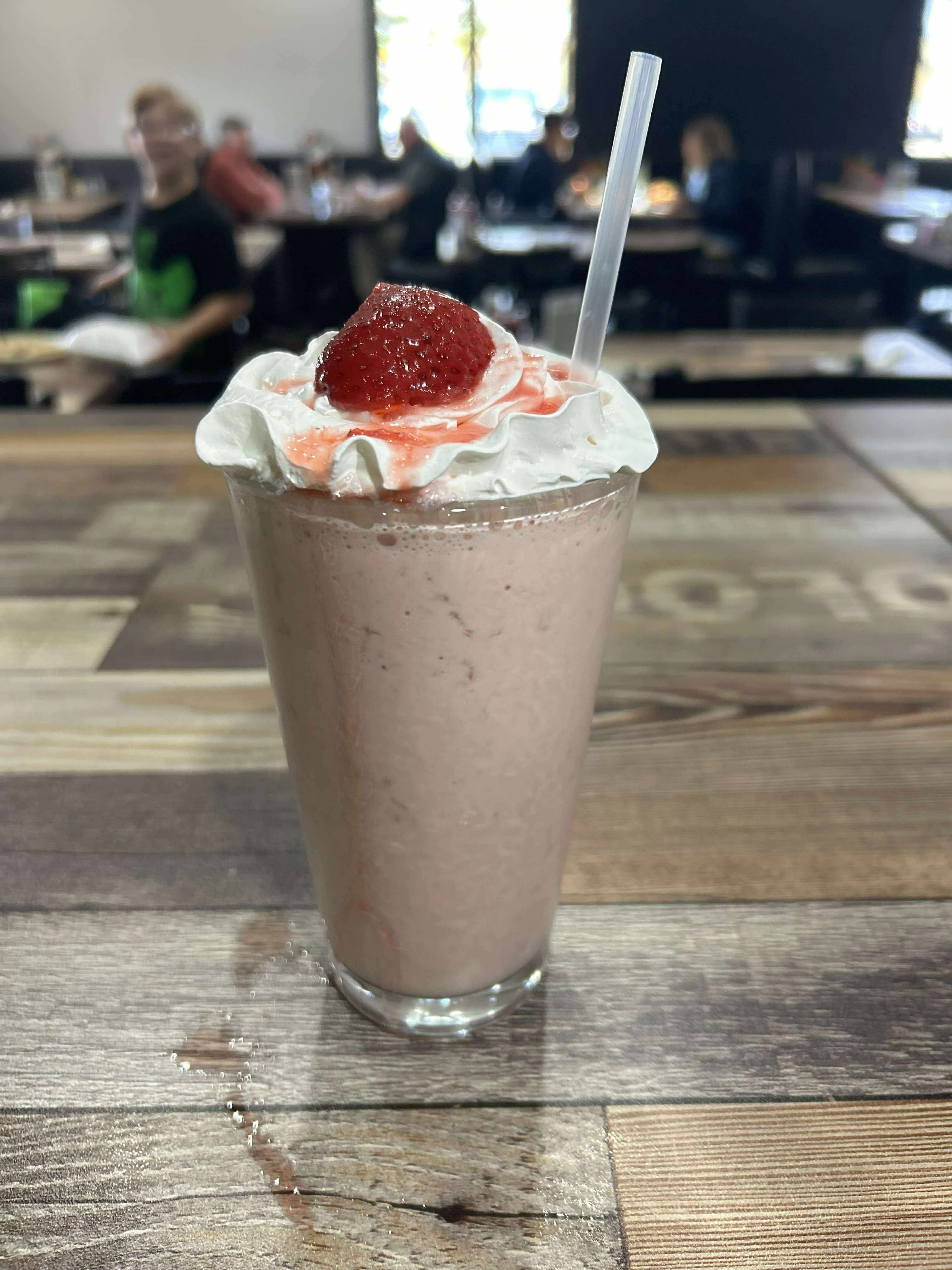 Strawberry milkshake topped with whipped cream and a cherry