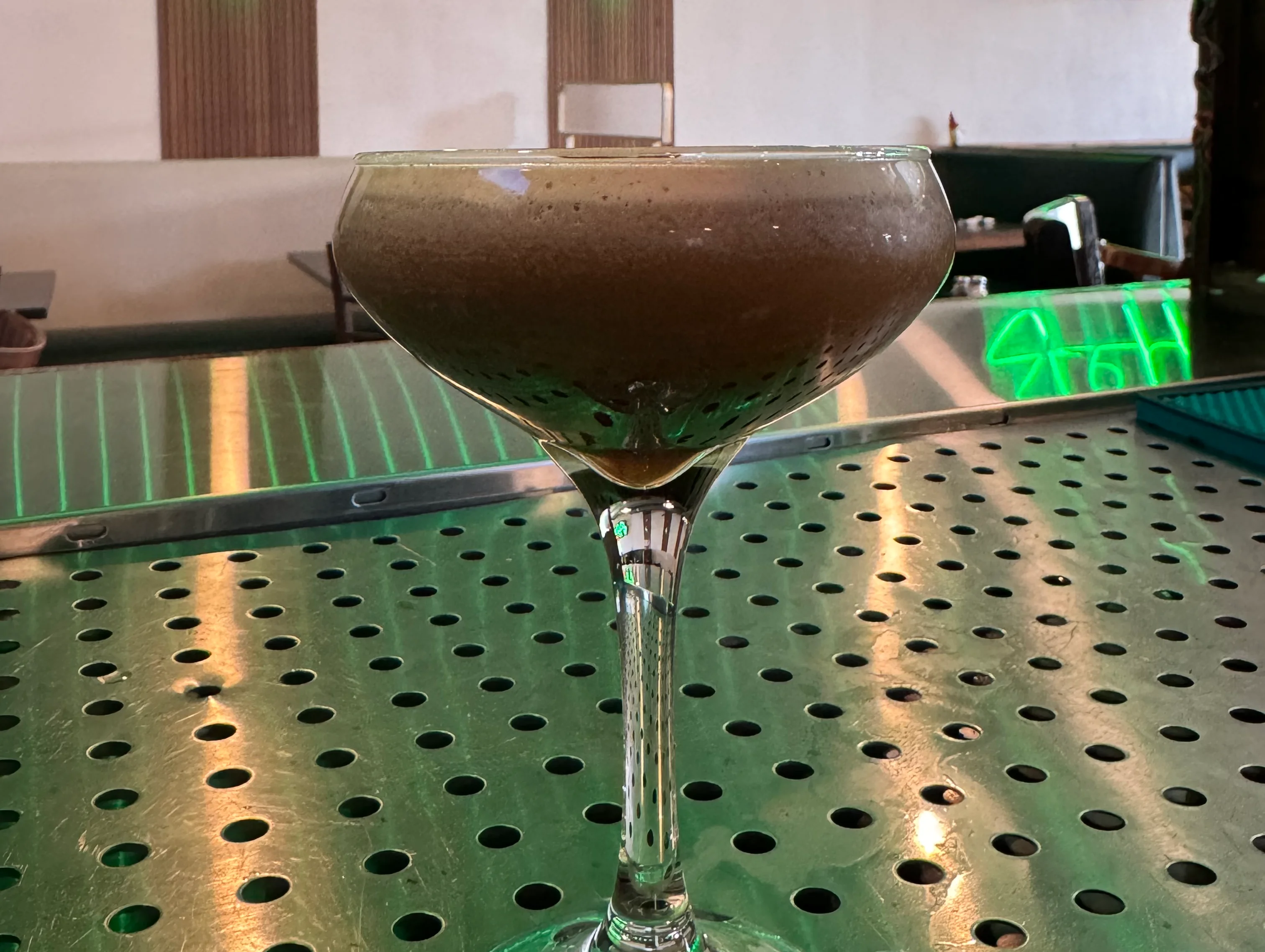 Bartender straining a cocktail into a glass at a bar.
