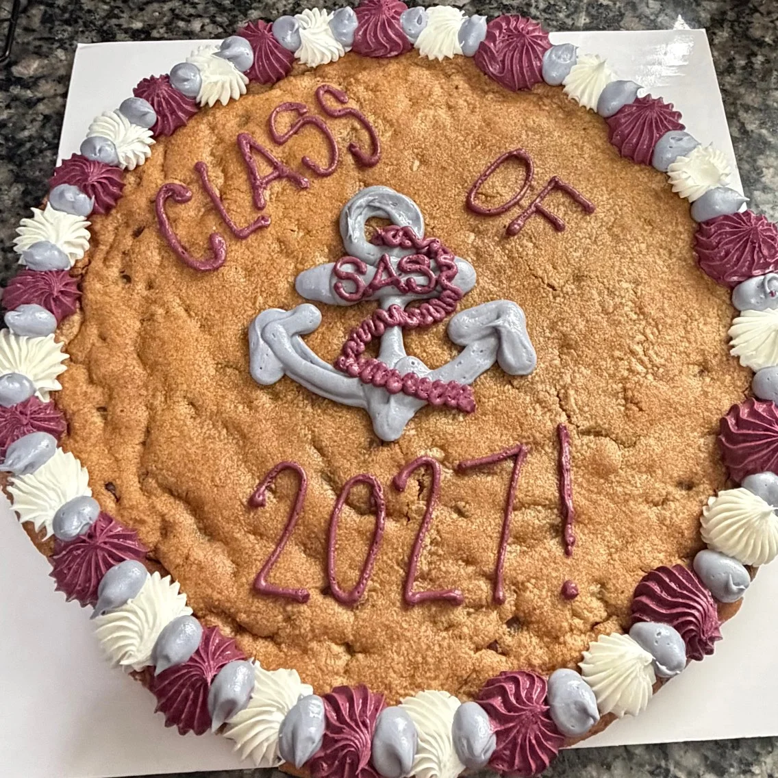 Graduation cookie cake decorated with purple and silver frosting