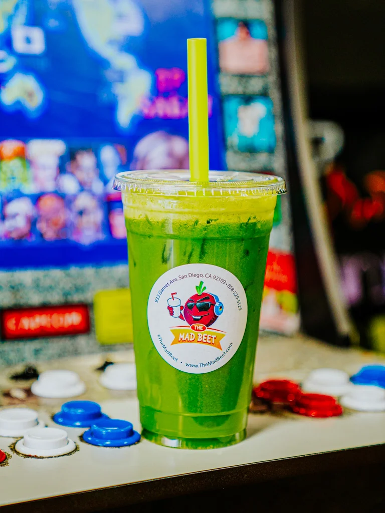 A Public Lemony Smoothie sitting on a classic arcade cabinet, in a disposable cup featuring The Mad Beet logo