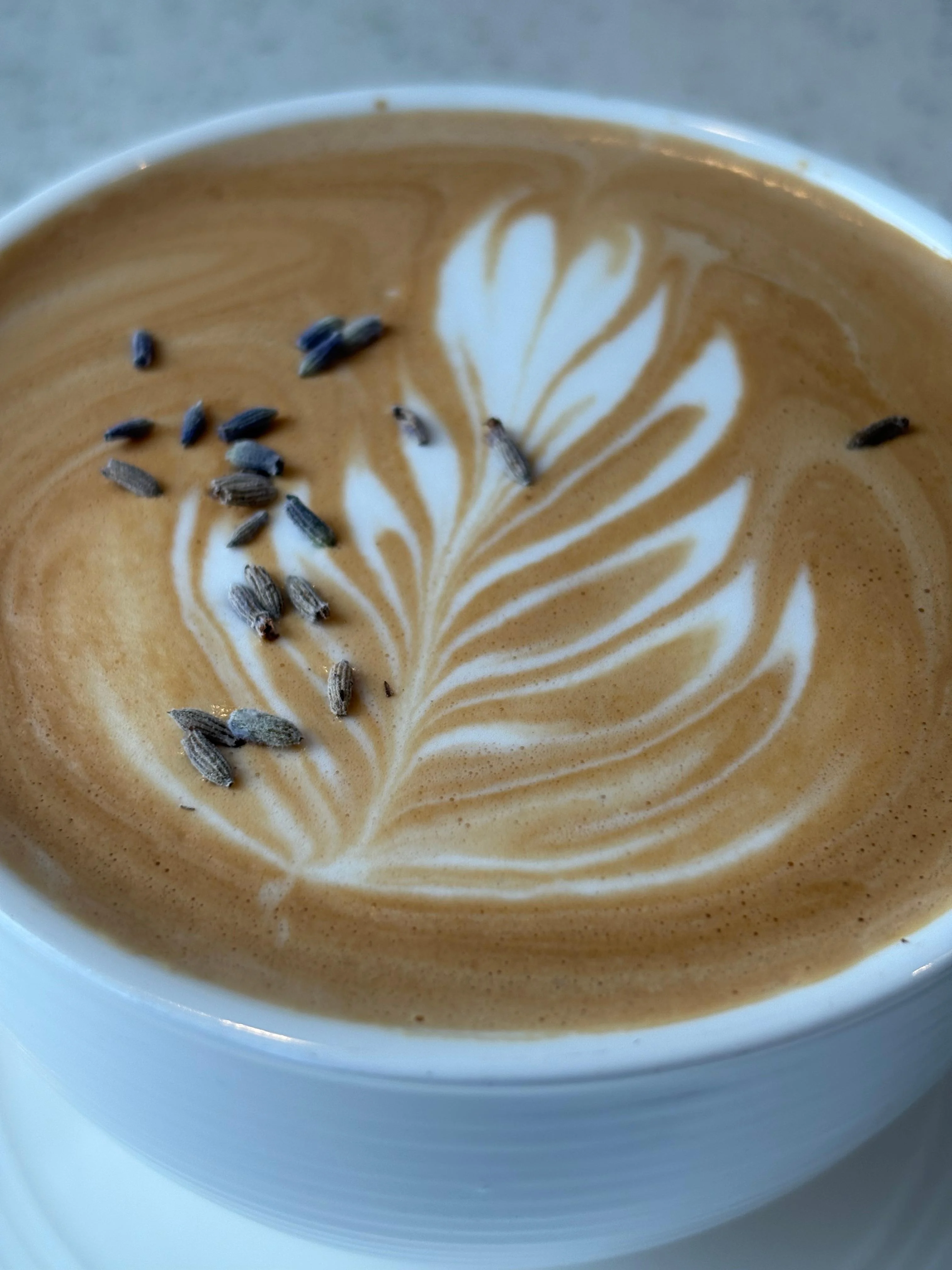 A beautifully crafted coffee drink topped with a delicate latte art design and sprinkled with lavender buds.