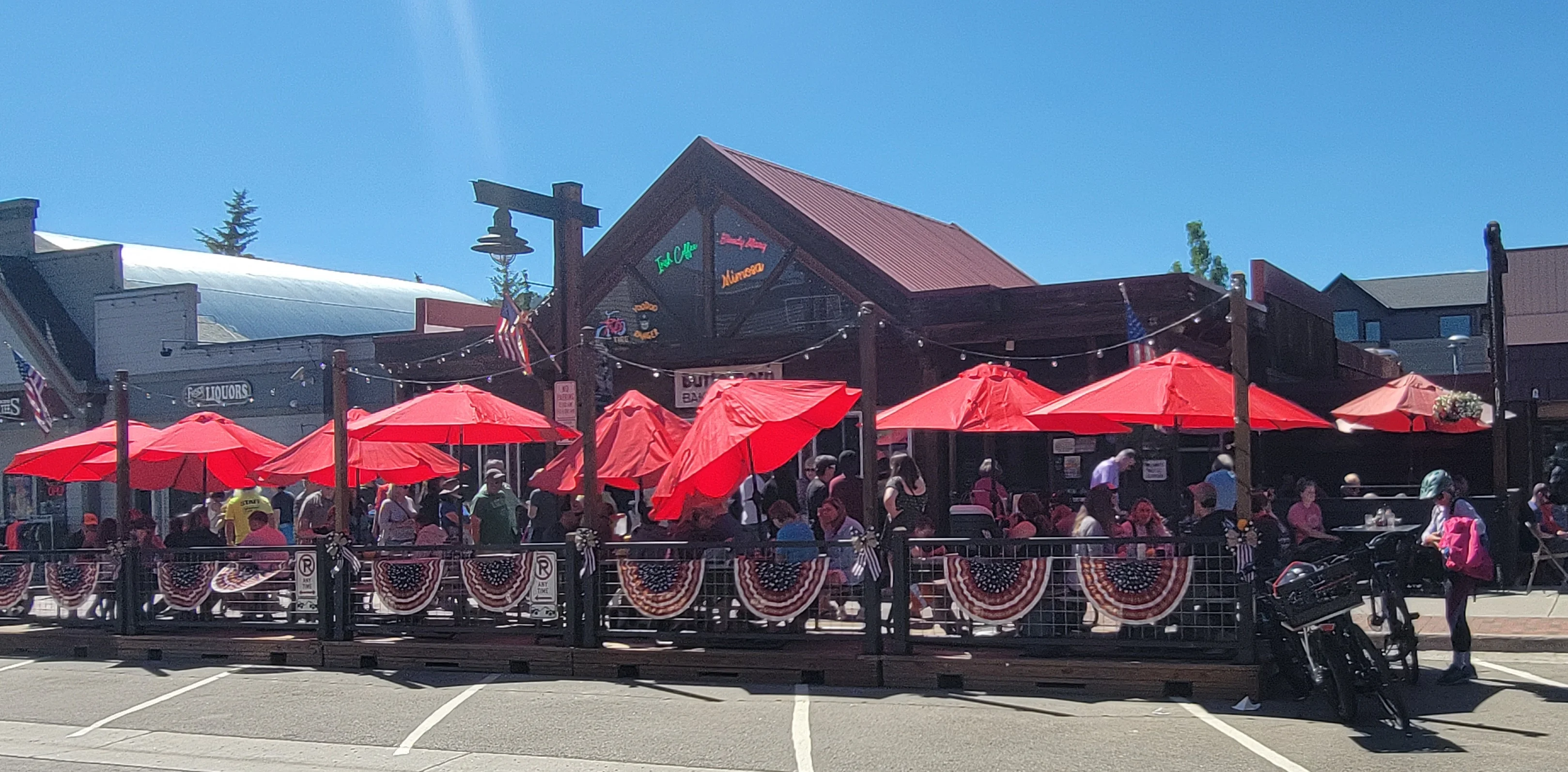 Busy restaurant patio with red umbrellas and festive decor
