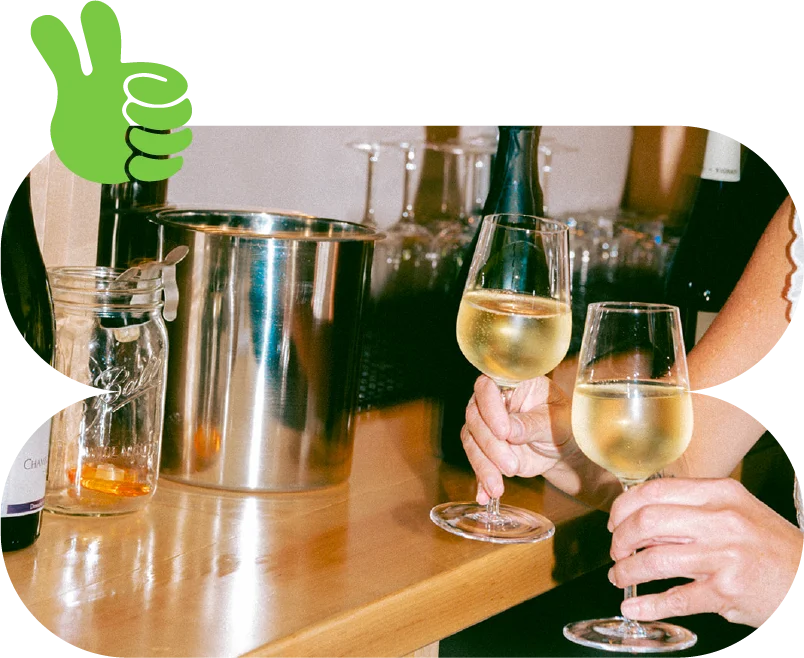 Two glasses of white wine clinking at a bar counter