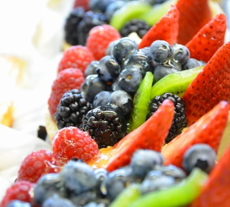 Delicious berry tarts topped with fresh berries and cream.