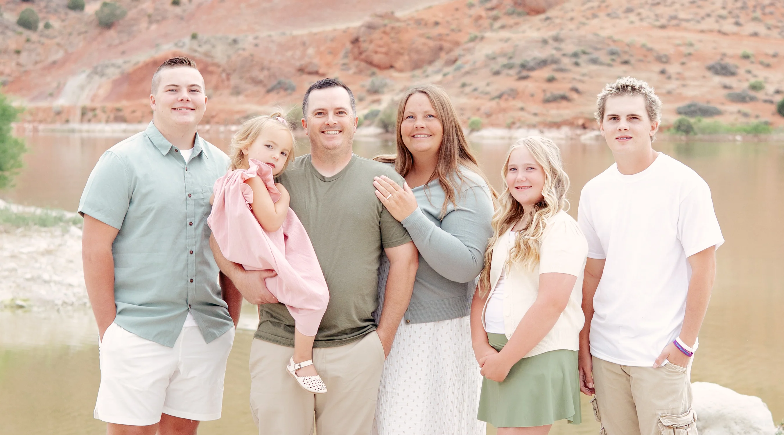 Family portrait by a serene lake with mountains in the background
