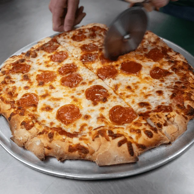 A pepperoni pizza being sliced up