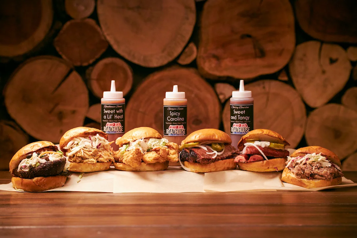 Assorted BBQ sandwiches with sauces on a wooden table