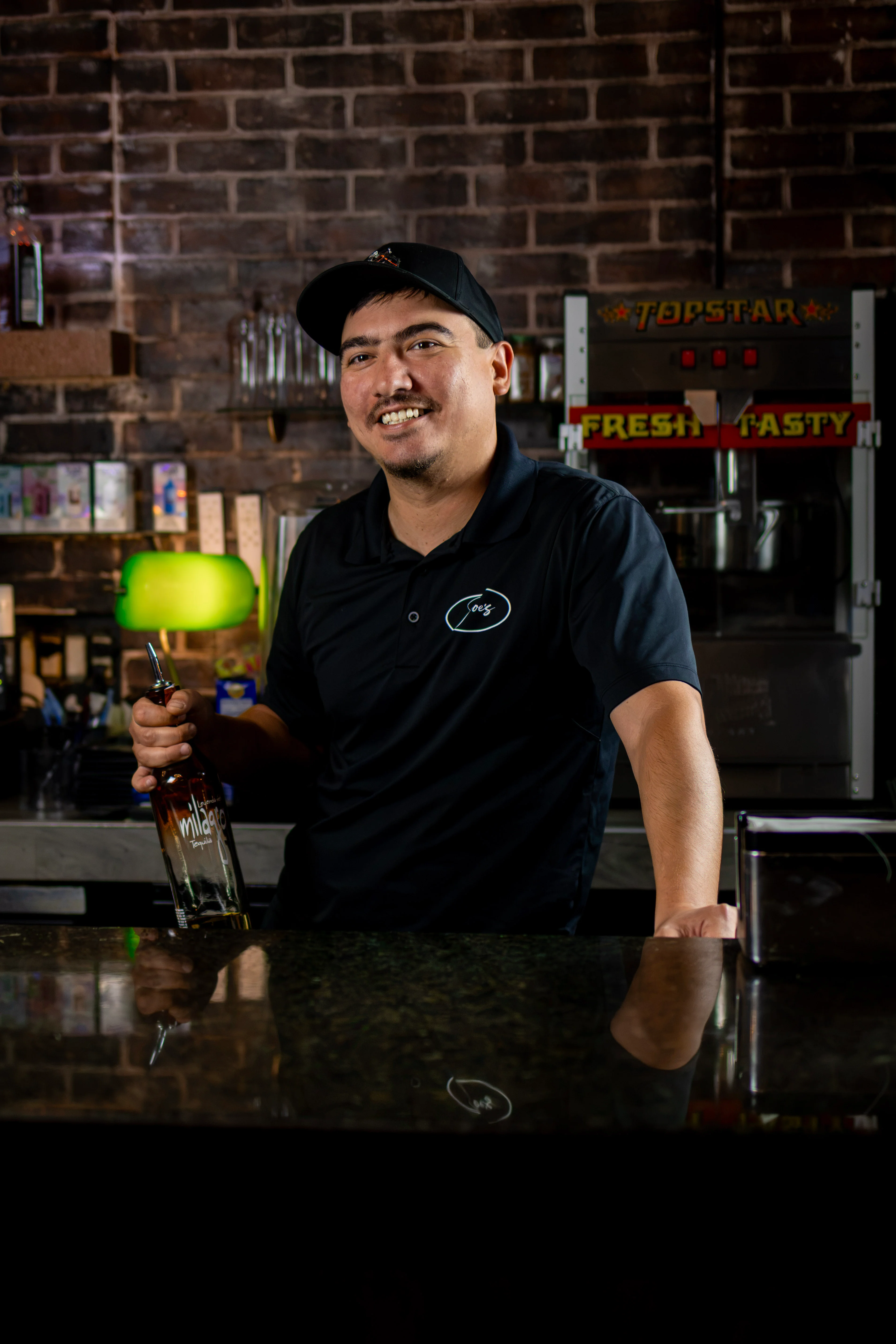 Bartender holding a tequila bottle behind a restaurant bar