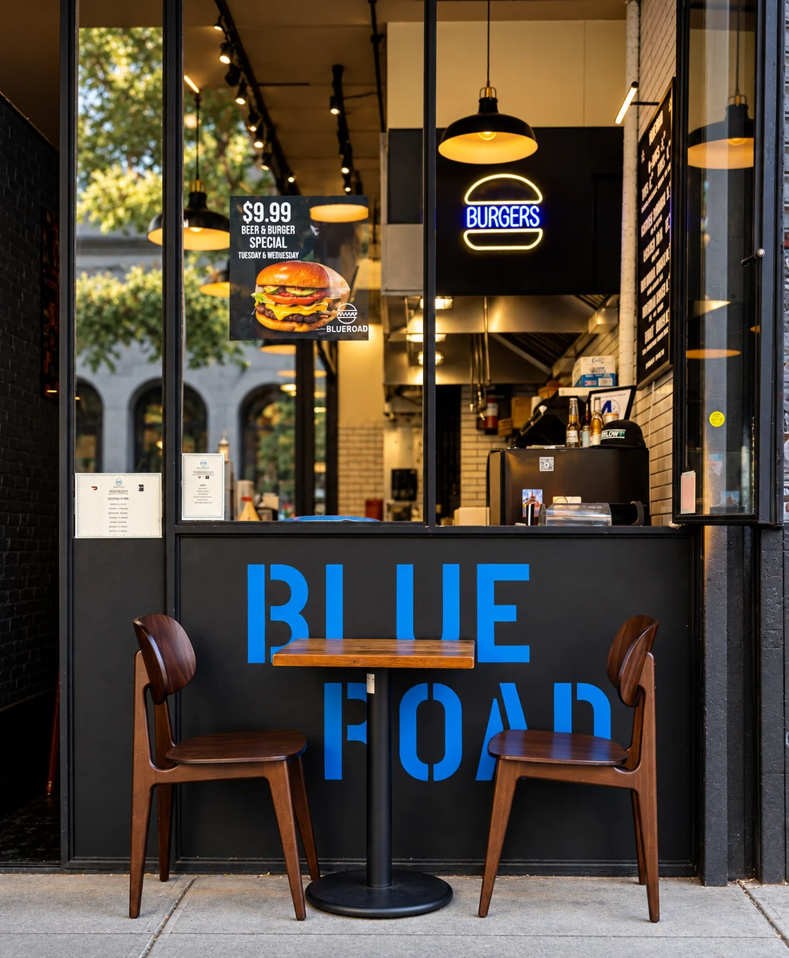 Modern burger restaurant storefront with outdoor bistro table and chairs