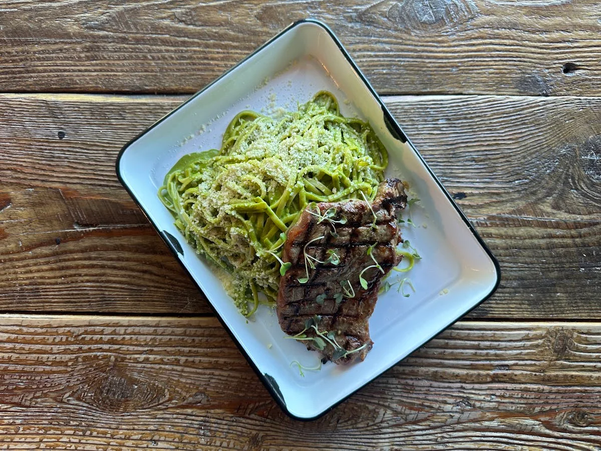 Grilled steak with pesto linguine on a rustic plate