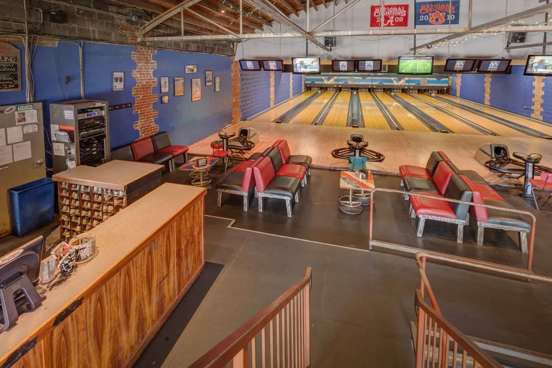 Interior of a modern bowling alley with multiple lanes and screens.