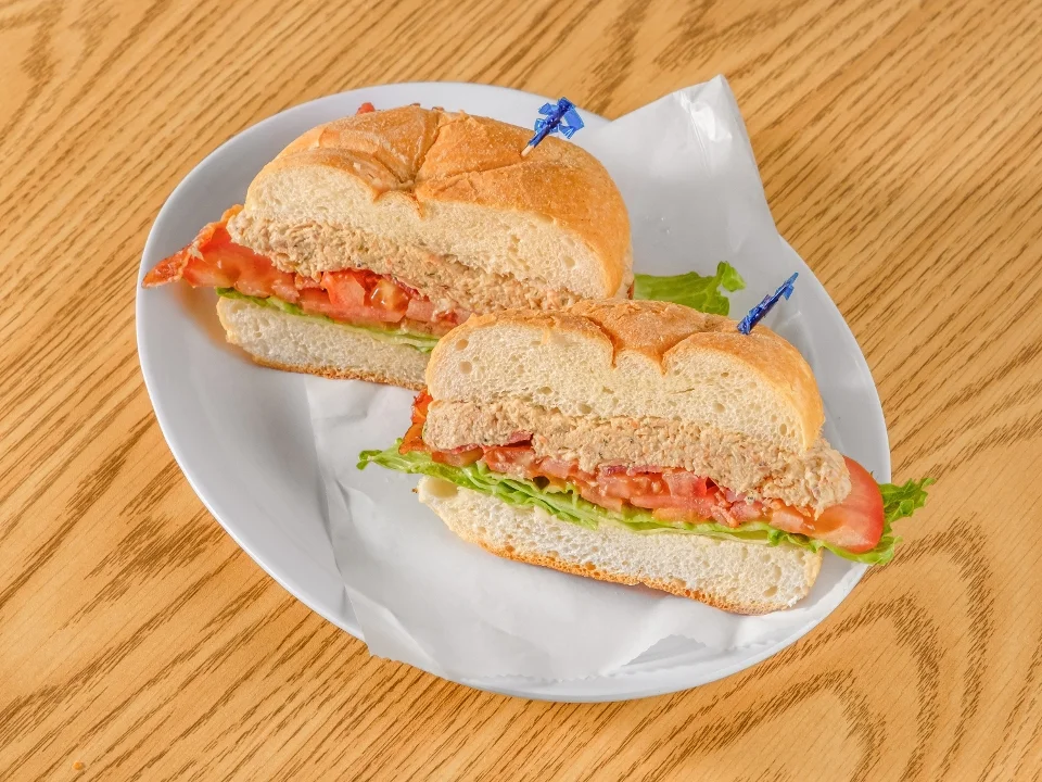 A plate with a sliced sandwich filled with lettuce, tomato, and a sandwich spread, garnished with toothpicks.