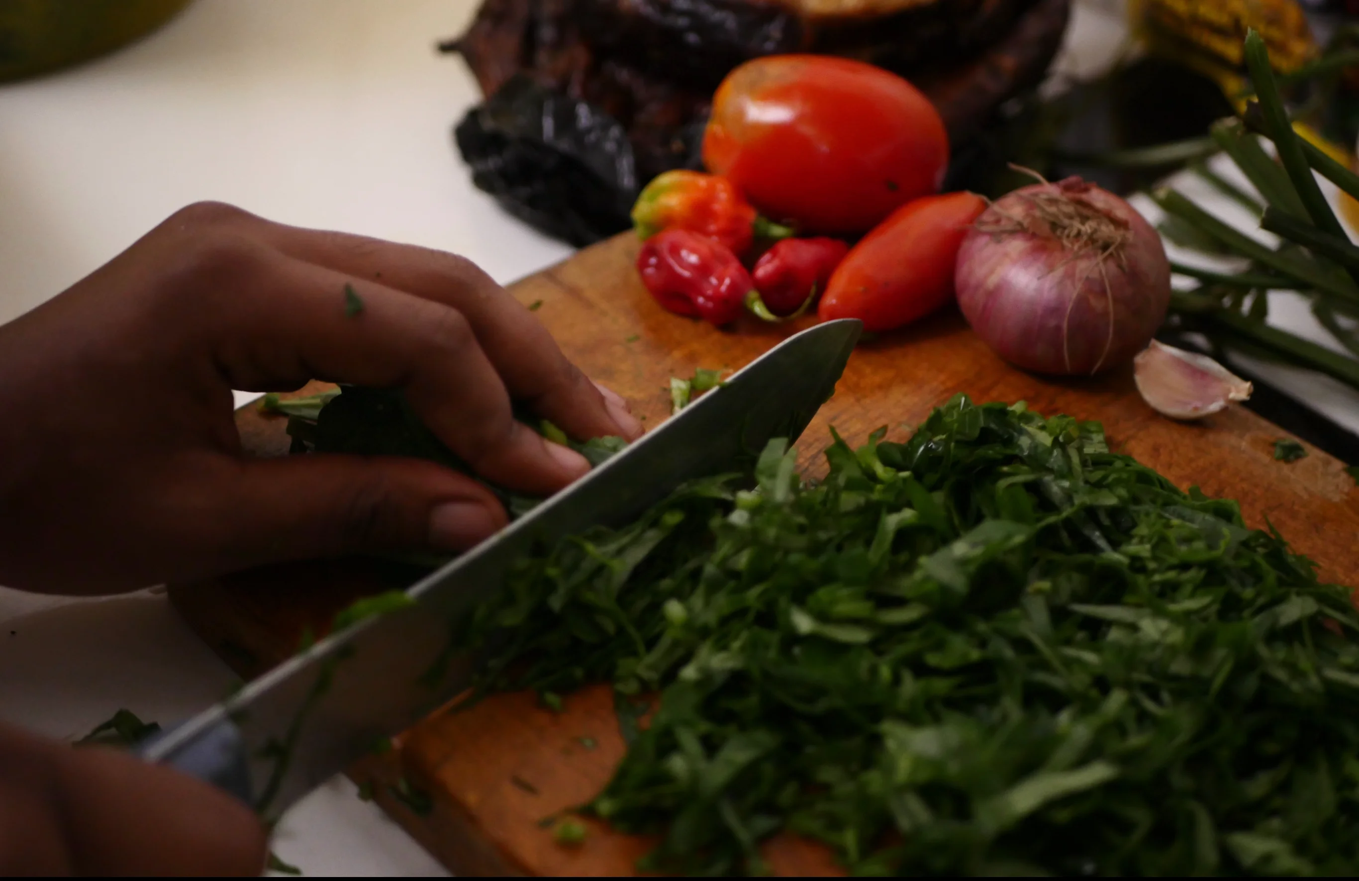 Cook cutting vegetables in kitchen at Tolex African Grill