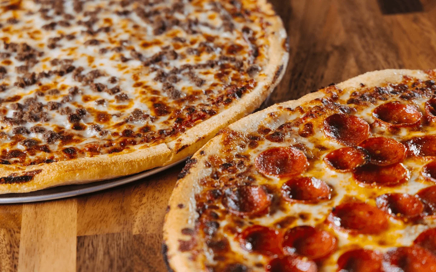 Pepperoni and beef pizzas on a wooden table