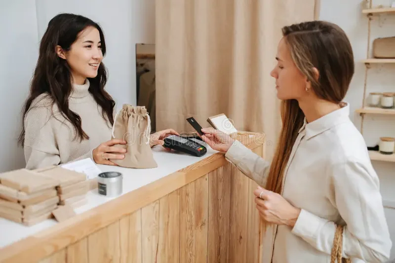 Customer making a payment at a retail counter with a friendly cashier.